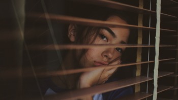 Isolation: a student peeks out of her blinds.