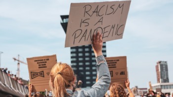 Protestor holds sign which reads "racism is a pandemic".