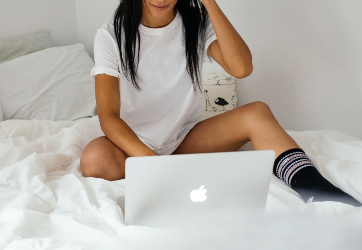A girl sits using a Macbook