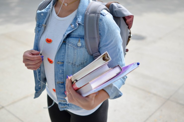 student carrying books and a back pack