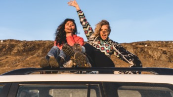 two girls sat on the top of a car