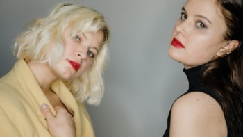 two women pose with red lipstick