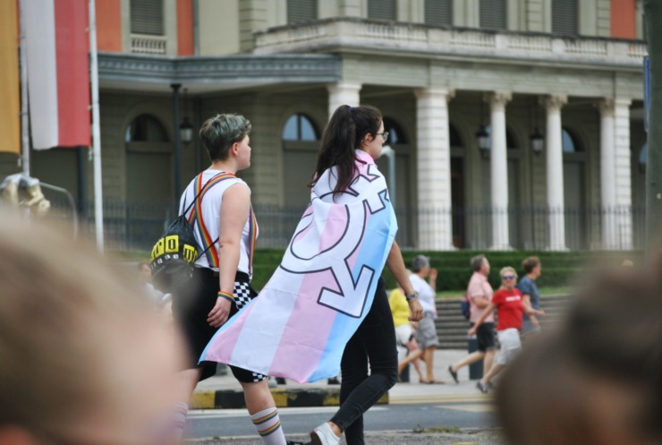 a person walks with a transgender flag