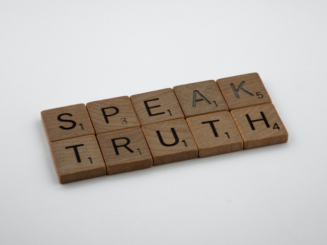 brown scrabble tiles spelling out 'speak truth'