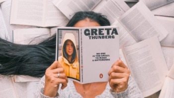 A girl reads a book by Greta Thunberg