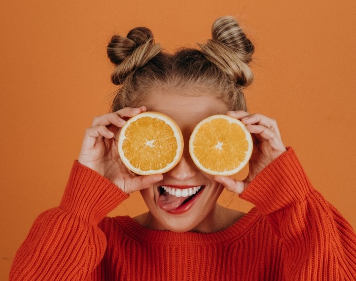 woman holding orange halves over her eyes