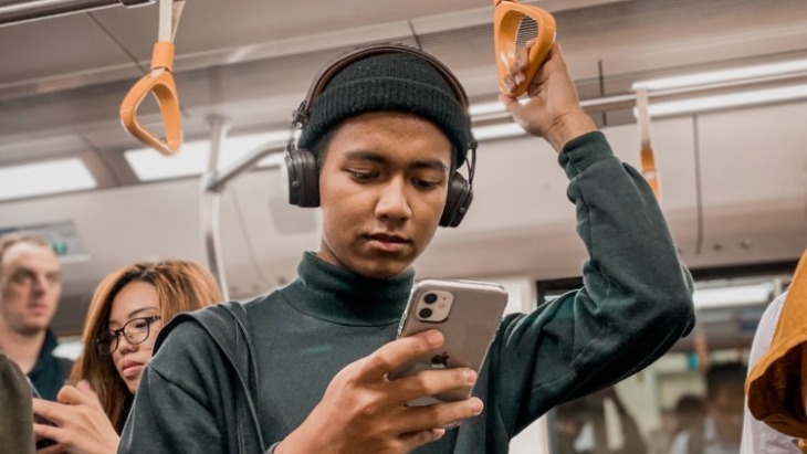 A boy browses his phone on a trian