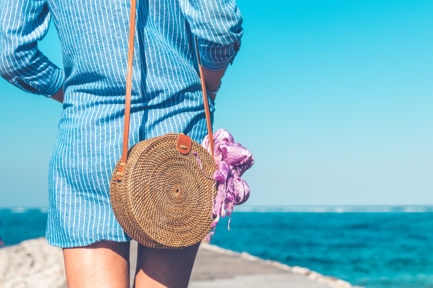 person walking by the sea with a bag and shirt dress